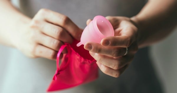 Young woman hands holding menstrual cup and small cotton bag