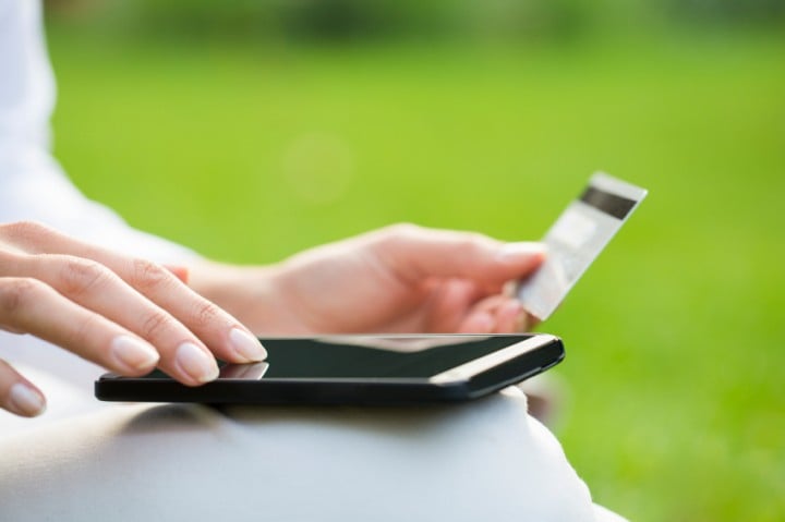 Close-up woman's hands holding a credit card and using cell phon