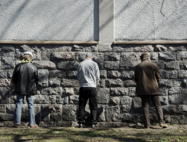 men urinating against wall
