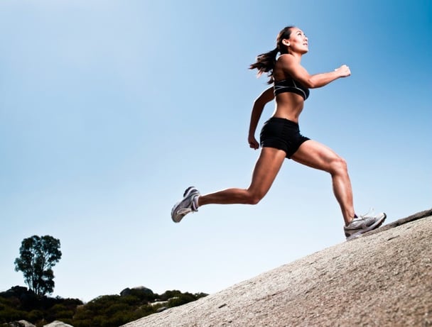 An elite athlete at peak action, running up a steep trail in the mountains.