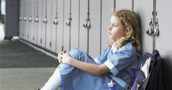 yong schoolgirl leaning against locker sad