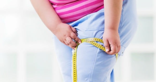 Overweight woman measuring her thigh after exercising.