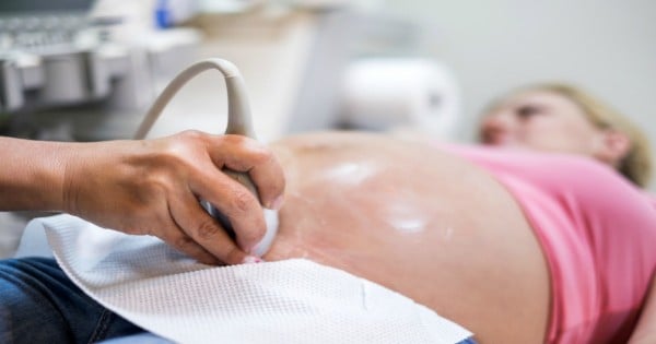 Unrecognizable gynecologist using ultrasound on pregnant woman.