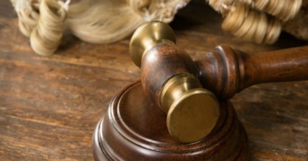 Wooden block, judge's wig and gavel on a wooden desk