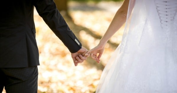 Closeup shot of young bride and groom holding hands at park