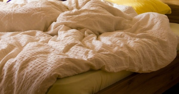 messy unmade bed with pillow and quilt cover
