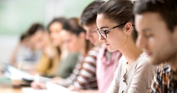 Group of students having a class. Focus is on young woman reading a book. [url=http://www.istockphoto.com/search/lightbox/9786738][/url]