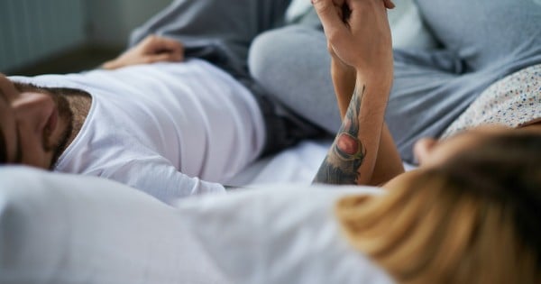 Couple lying in bed holding hands