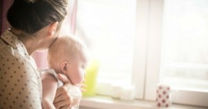 woman and baby looking out the window image via istock