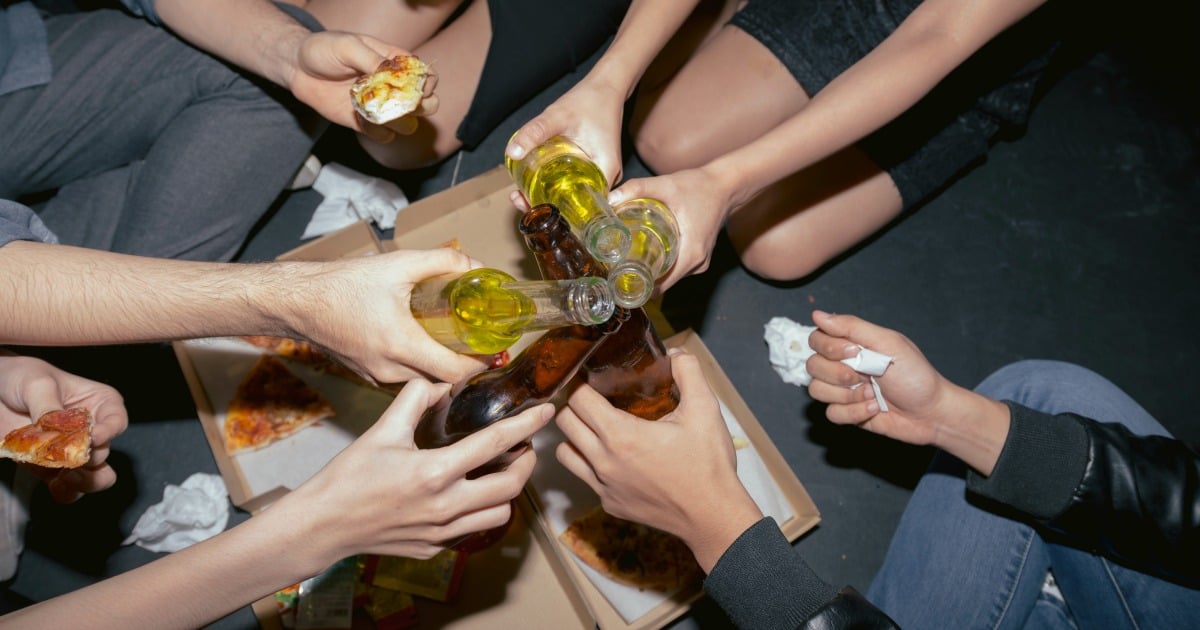 Young people drinking beer and eating pizza at the party