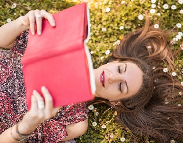 woman reading book in grass