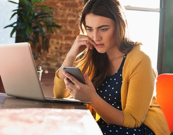 young woman stressed at work laptop phone