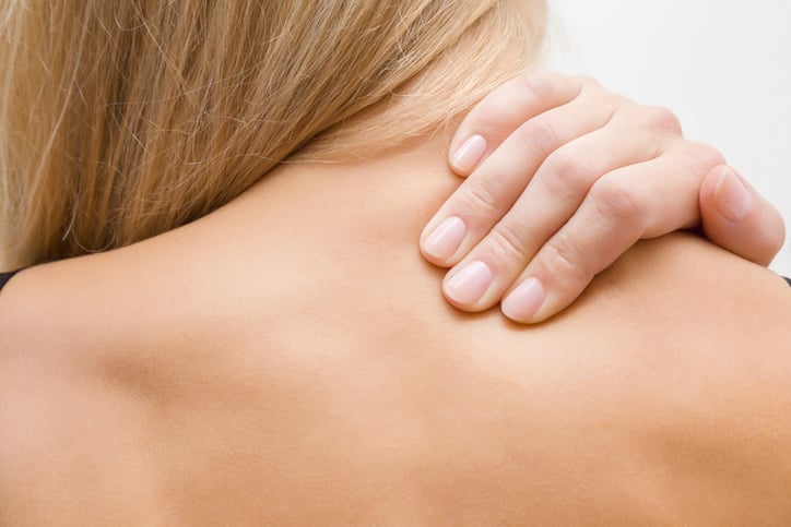 Woman with back pain rubbing back with fingers, osteopathy treatment