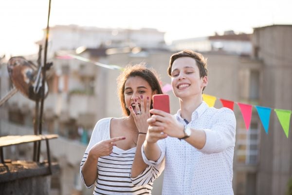 Young couple taking selfie of engagement ring
